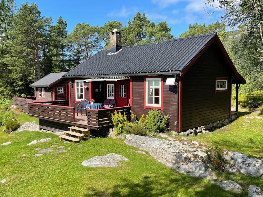 a red cabin with a porch and a deck at Sjarmerende hytte omgitt av vakker natur in Molde