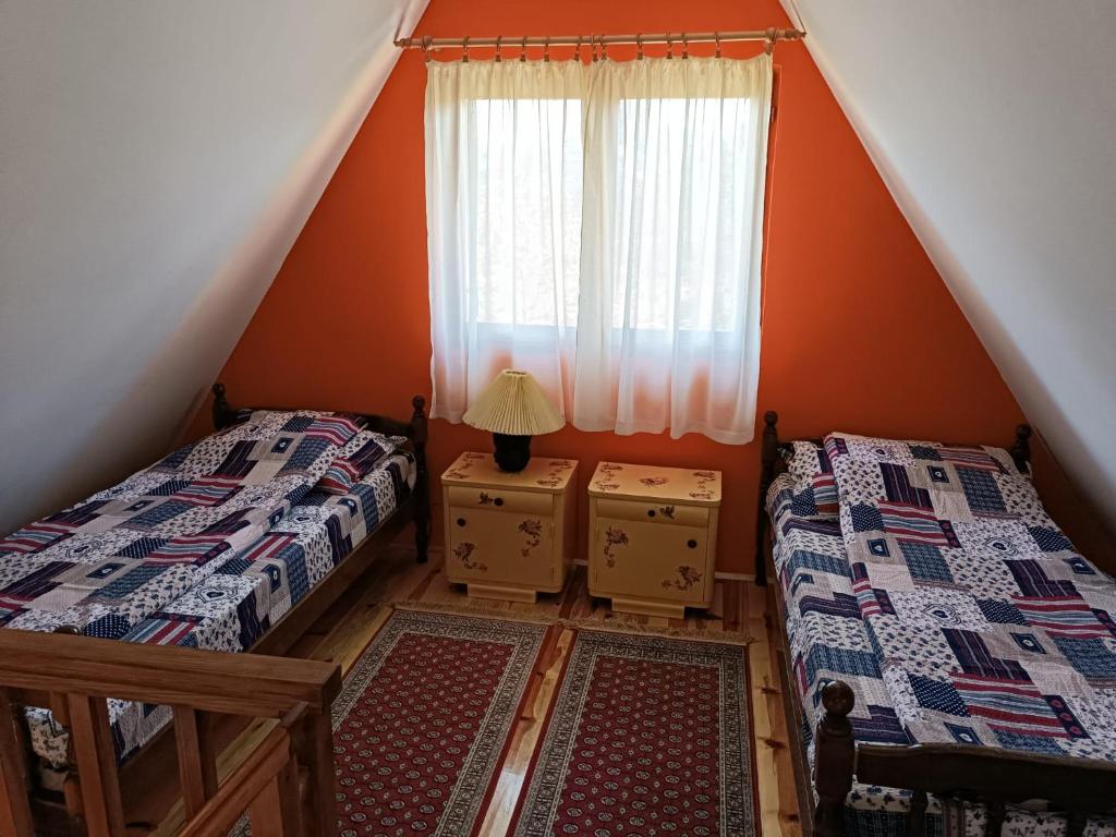 - une chambre mansardée avec 2 lits et une fenêtre dans l'établissement Vila Mitrović, à Bajina Bašta