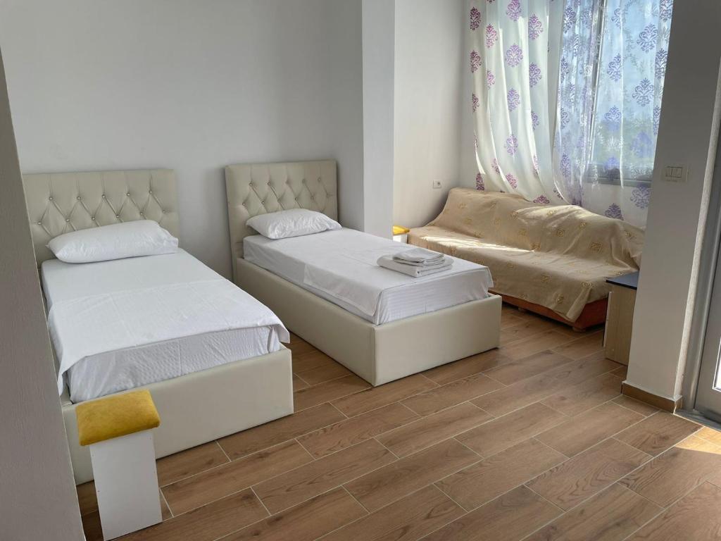 twee bedden in een kleine kamer met houten vloeren bij AMANTIUS APARTMENTS in Borsh