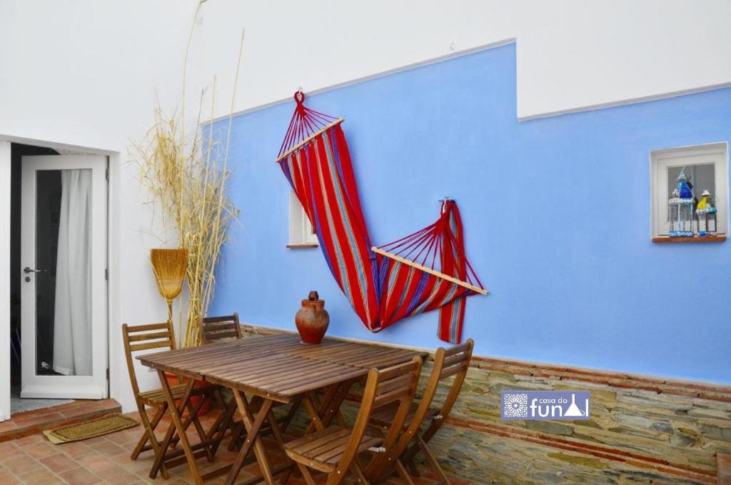 una mesa de madera con dos sombrillas colgadas de una pared azul en Casa do Funil, en Mértola