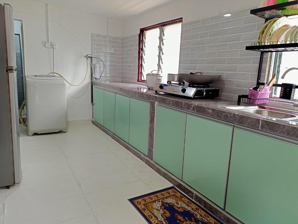 Bandar  Pusat JengkaにあるHomestay Bakti @Rantau Perintisのキッチン(緑のキャビネット、冷蔵庫付)