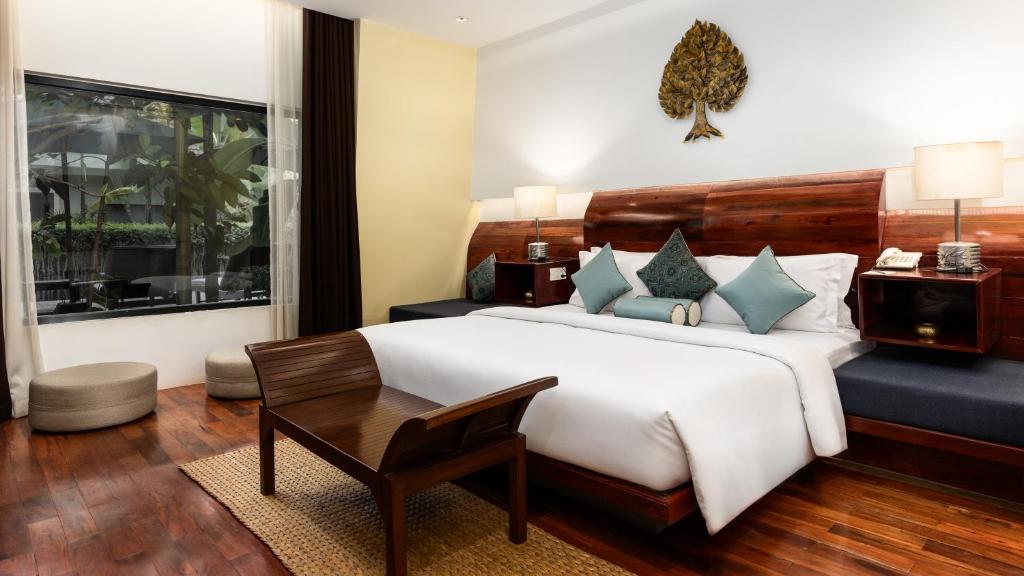 a bedroom with a large white bed and a table at Lynnaya Urban River Resort in Siem Reap