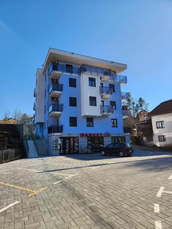 ein weißes Gebäude mit einem davor geparkten Auto in der Unterkunft PIK Apartmani in Vrnjačka Banja