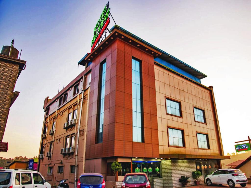 a building with cars parked in front of it at STAYMAKER Hotel Hill View in Madikeri