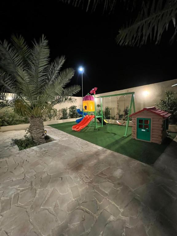 a backyard at night with a playground and a house at شالية السحاب in Al Ḩazm
