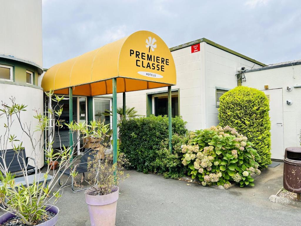 a restaurant with a yellow awning and plants at Premiere Classe Bordeaux Sud Pessac Bersol in Pessac