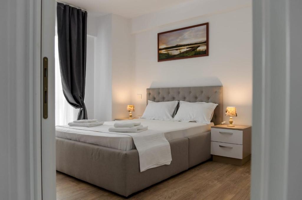 - une chambre blanche avec un grand lit et deux lampes dans l'établissement Luxury Studios & Apartments Newton by GLAM, à Iaşi