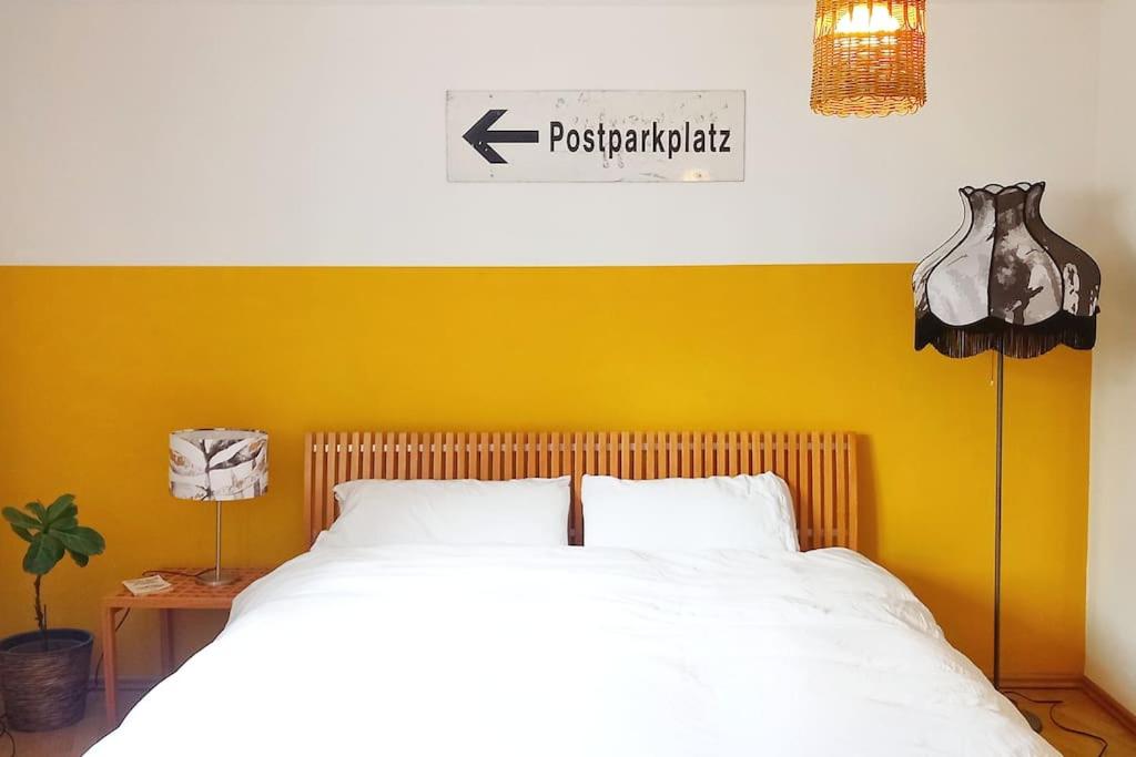 1 dormitorio con cama blanca y pared amarilla en Casa Ane - Gäste Apartment, en Renningen