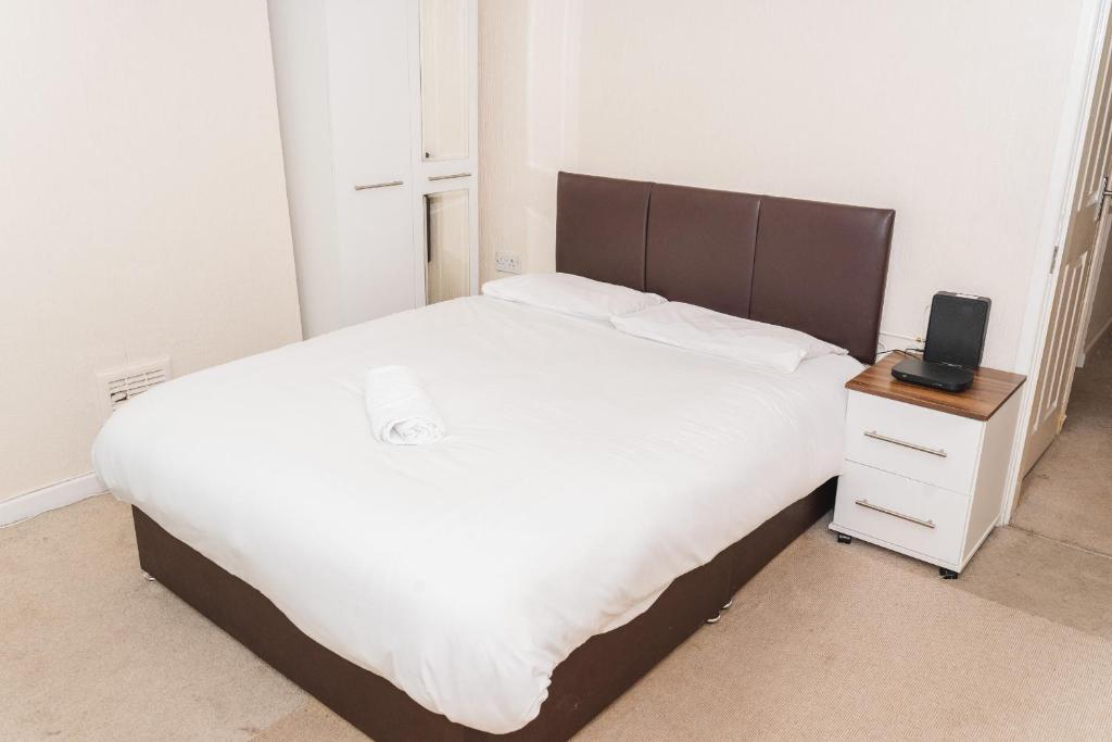 a bedroom with a large white bed and a night stand at City Rooms in Stoke City in Stoke on Trent