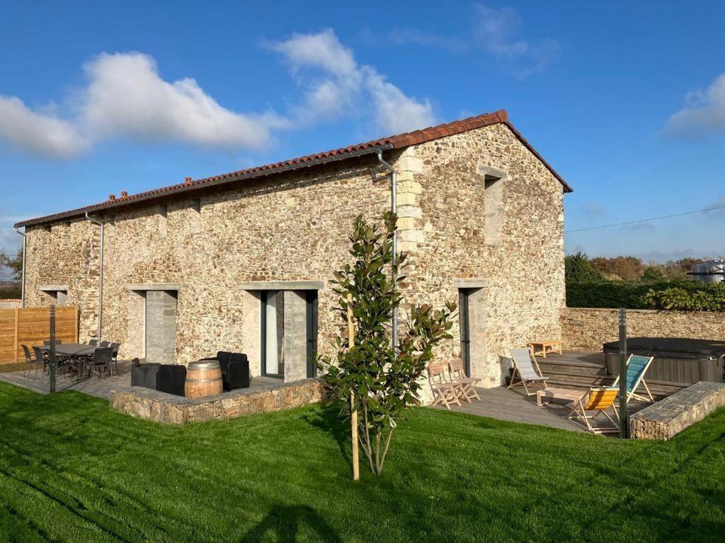 Cette grande maison en pierre dispose d'une cour avec une pelouse. dans l'établissement Grand Bretonnerie, à La Haie-Fouassière