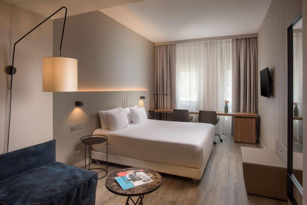 a hotel room with a bed and a couch at NH Trieste in Trieste