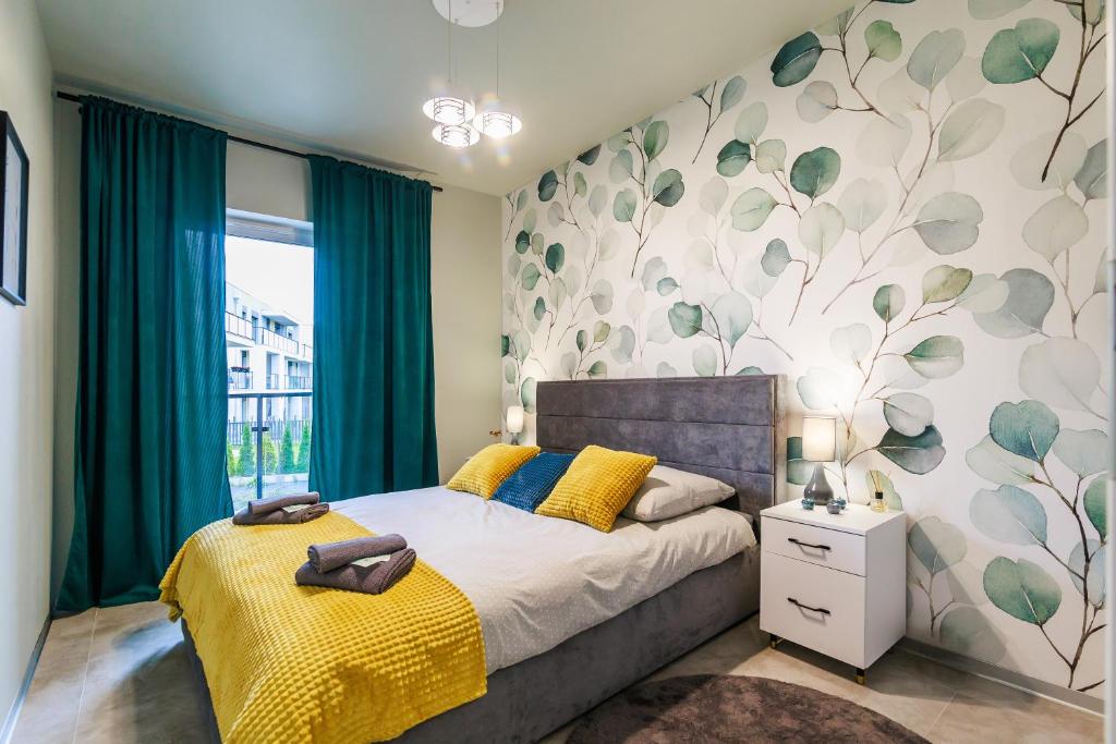 - une chambre avec un lit et un mur orné de feuilles vertes dans l'établissement Zielono Mi, à Słupsk