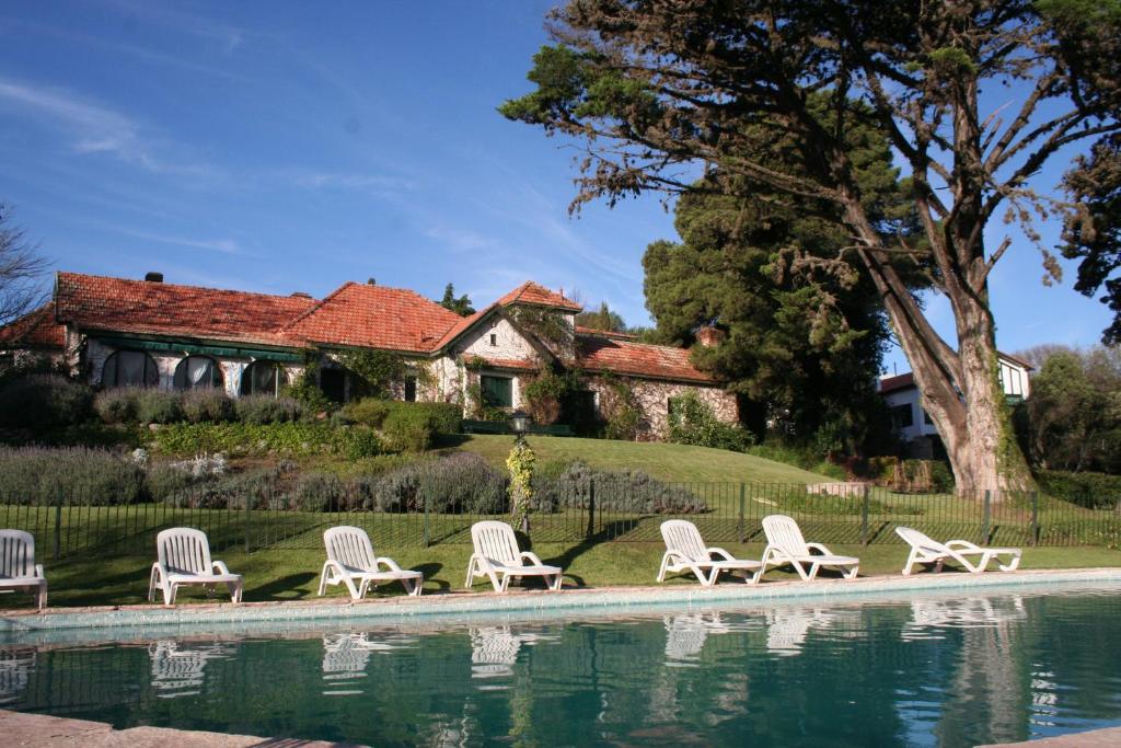 un grupo de sillas junto a una piscina frente a una casa en Posada los Cedros en La Cumbre