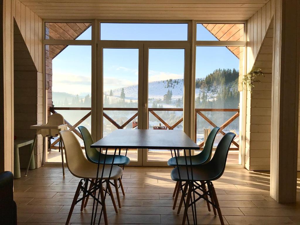 einen Tisch und Stühle in einem Zimmer mit einem großen Fenster in der Unterkunft Friends house bukovel in Bukowel