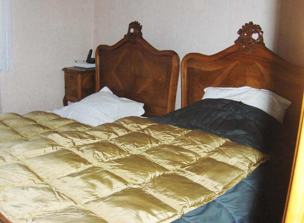 ein Bett mit zwei Kopfteilen aus Holz in einem Schlafzimmer in der Unterkunft Brasserie de l'Eichel-t-Ale in Voellerdingen