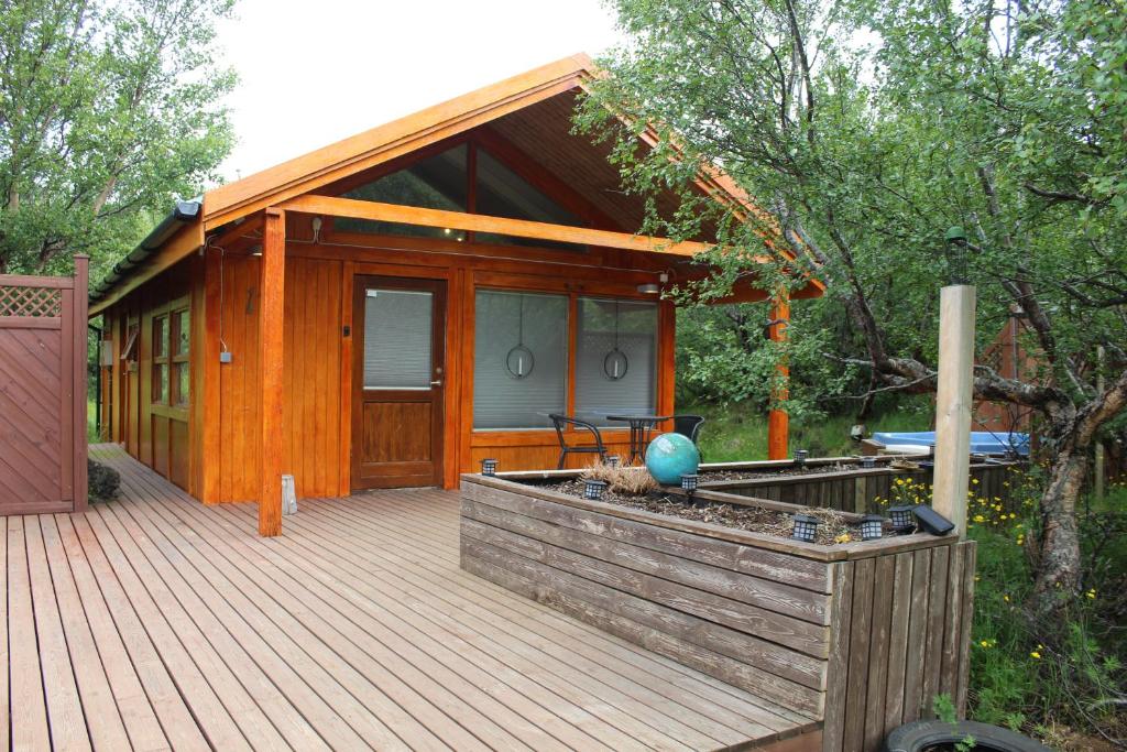 a wooden cabin with a deck with a table on it at Relaxing and cozy cottage with hot tub in Húsafell