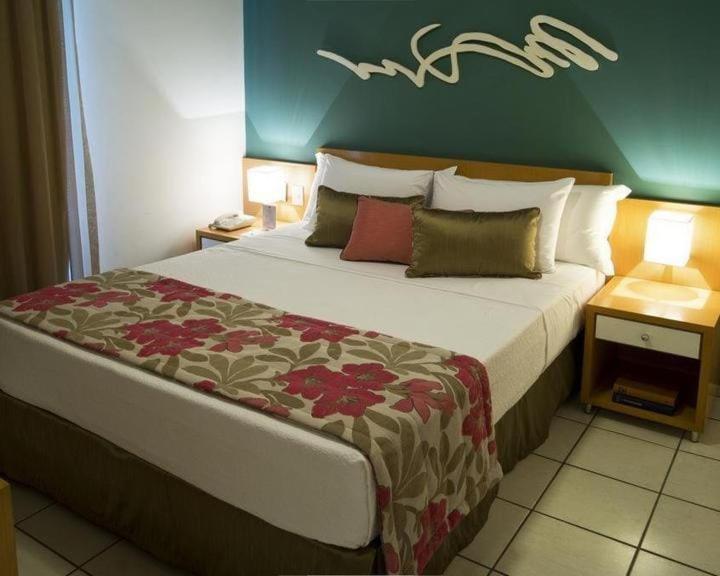 a bedroom with a large bed with a green wall at Praia do Canto Apart Hotel - Apto 405 - Varanda Lateral com Vista Mar in Vitória