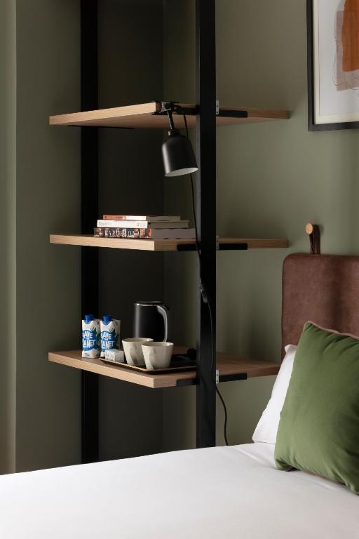 a room with a bed and a shelf with cups and a lamp at TOC Hotel Las Ramblas in Barcelona