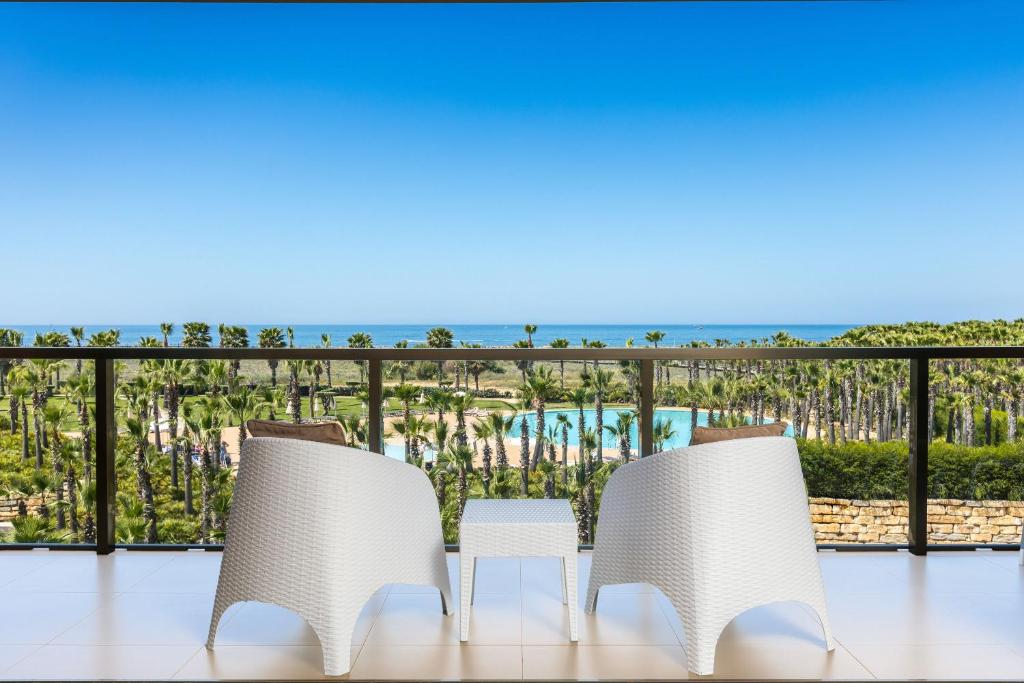 two chairs and a table on a balcony with the ocean at NAU Salgados Dunas Suites in Albufeira