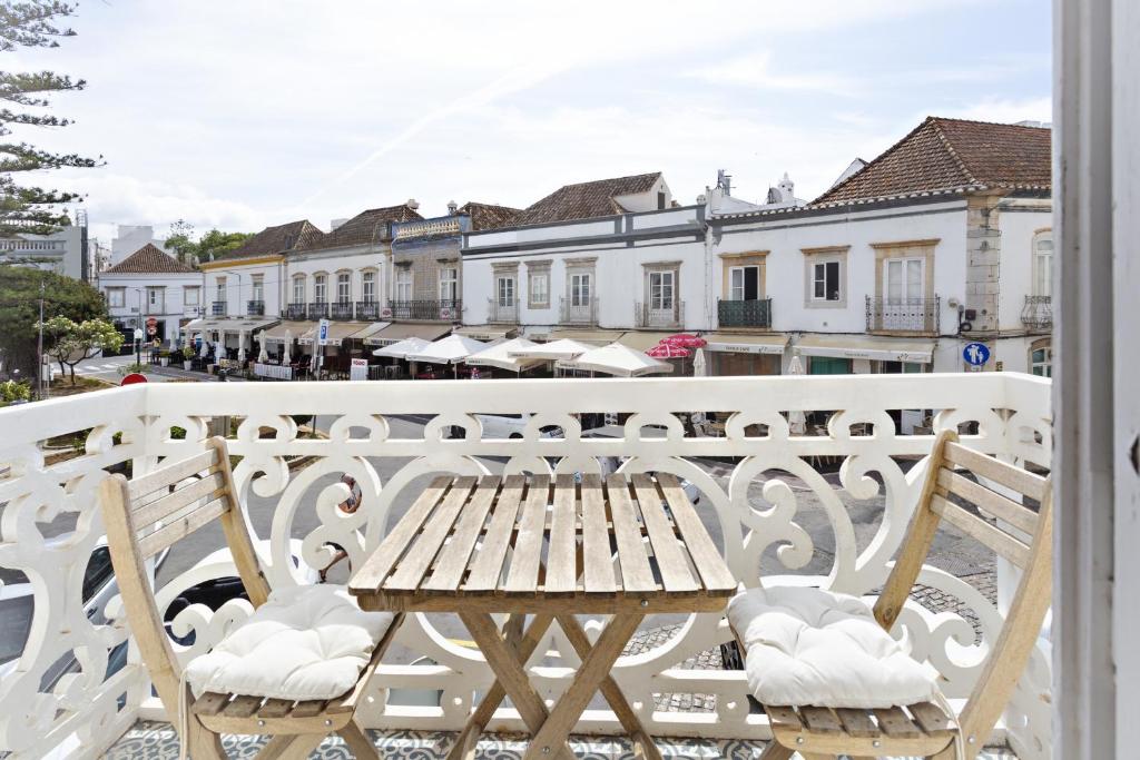 a wooden table and chairs on a balcony at Alagoa Apartments in Tavira