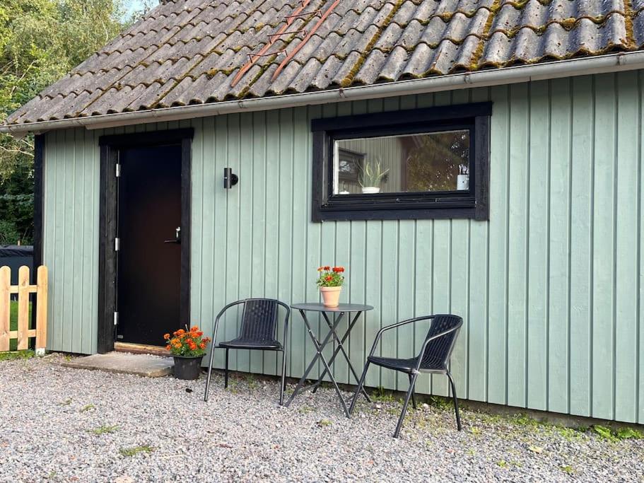 een tafel en twee stoelen voor een groen gebouw bij Araya Svensson’s Guest House in Falkenberg