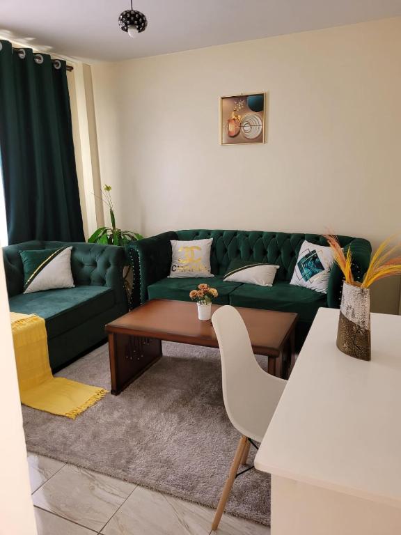 ein Wohnzimmer mit einer grünen Couch und einem Tisch in der Unterkunft Lux Suites Supaboma Apartments Embakasi in Nairobi