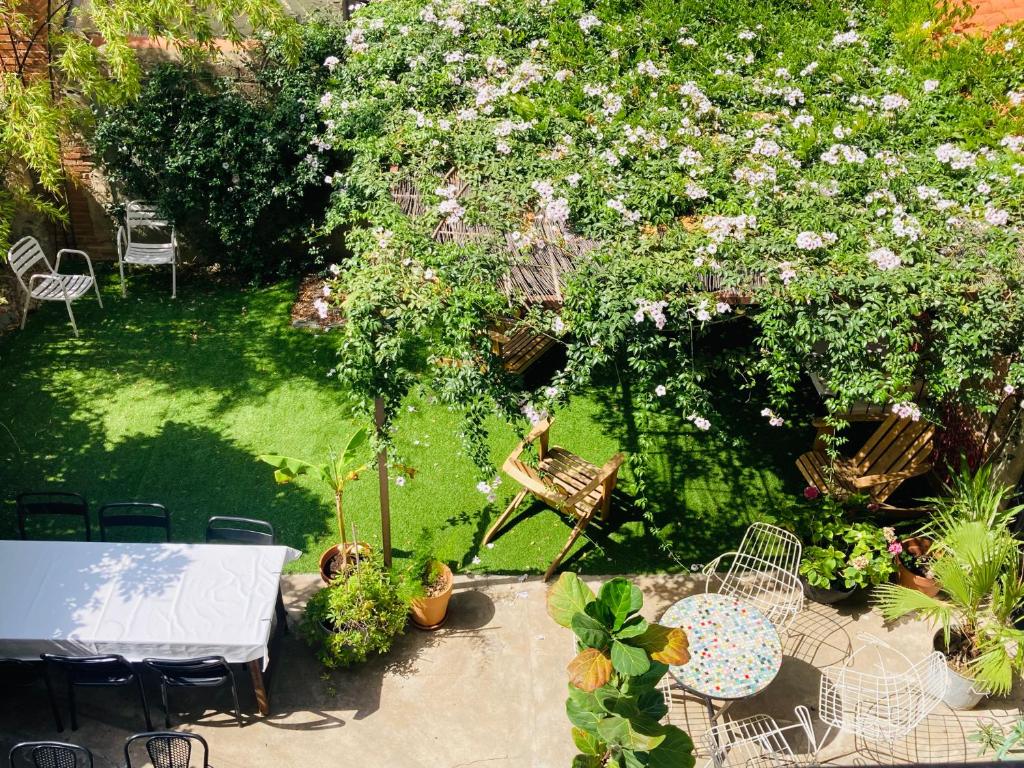 einen Tisch und Stühle in einem Garten mit Blumen in der Unterkunft Les Cagettes en Ville in Perpignan