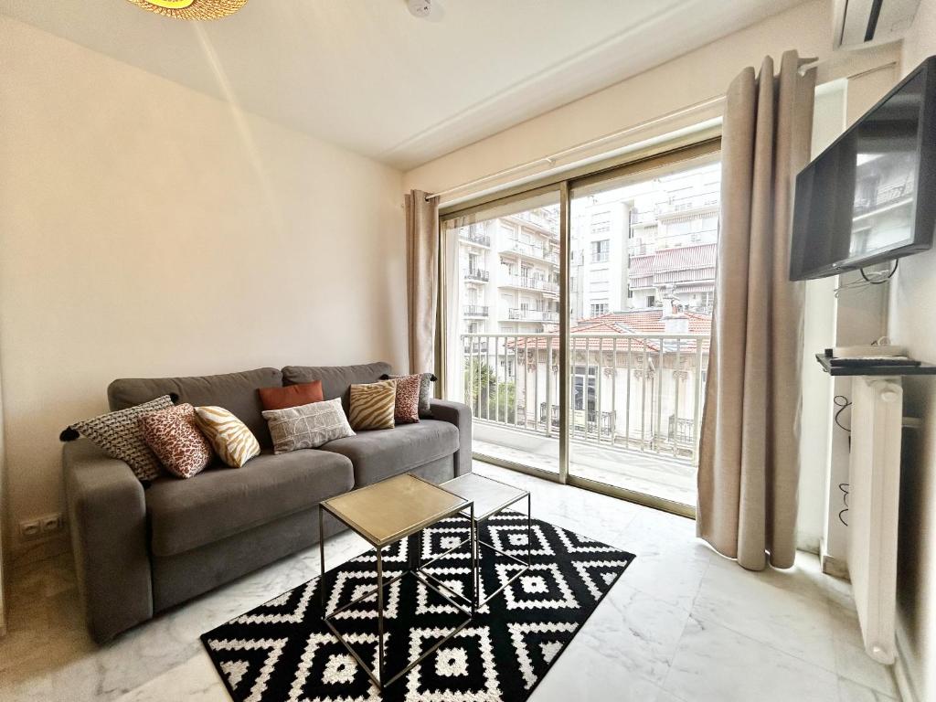 un salon avec un canapé et une grande fenêtre dans l'établissement ApartHotel Riviera - Nice Carré d'Or - Large studio AC Terrasse - Très calme - BALCON BERLIOZ 2, à Nice