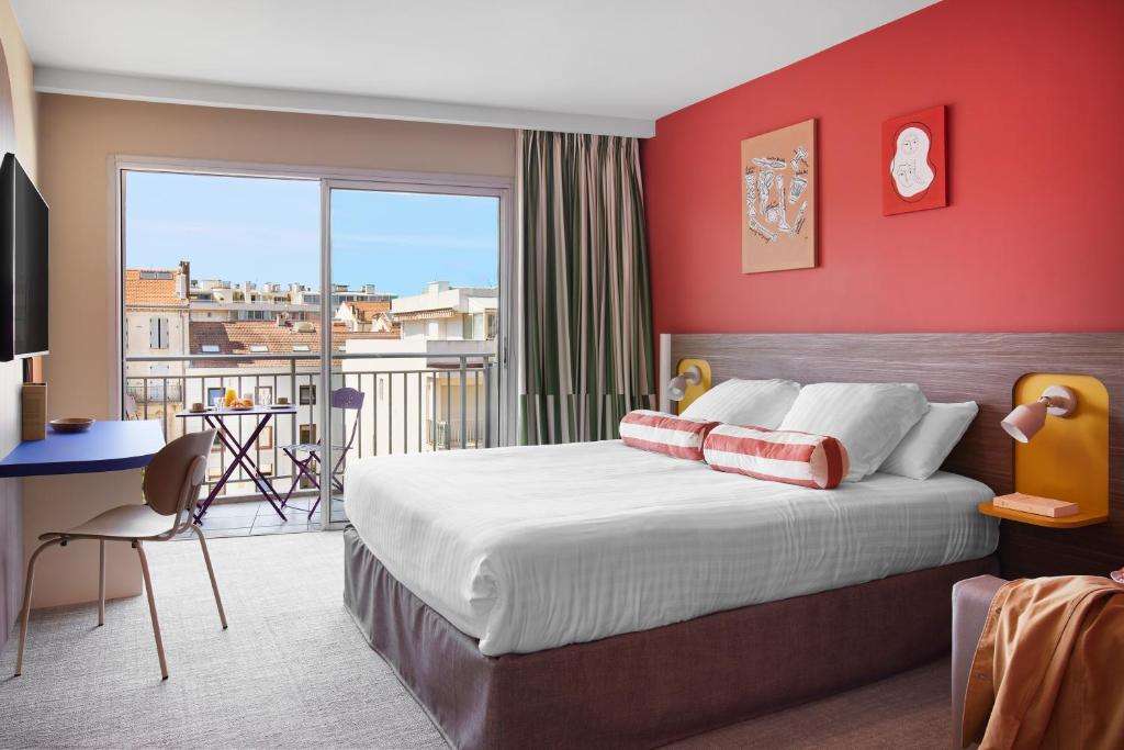 a bedroom with a large bed with a red wall at Hotel Abrial in Cannes