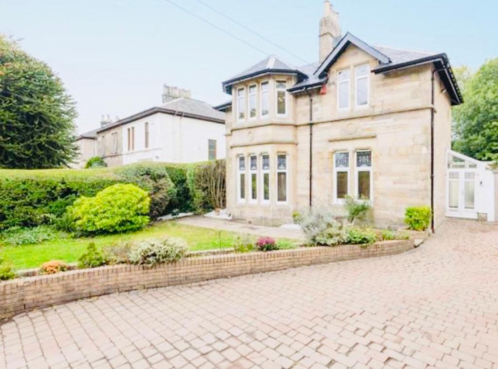 a large house with a brick driveway in front of it at Carlibar Villa in Barrhead