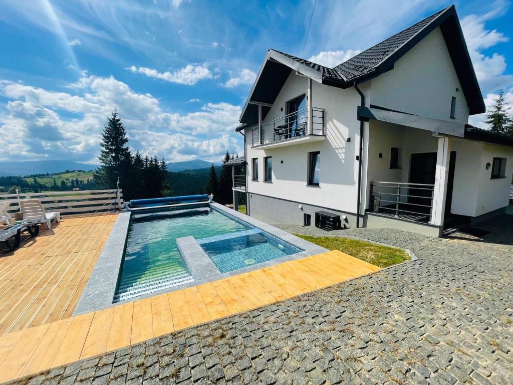 a house with a swimming pool next to a house at Lidia chalets in Polyanitsa Popovichevskaya