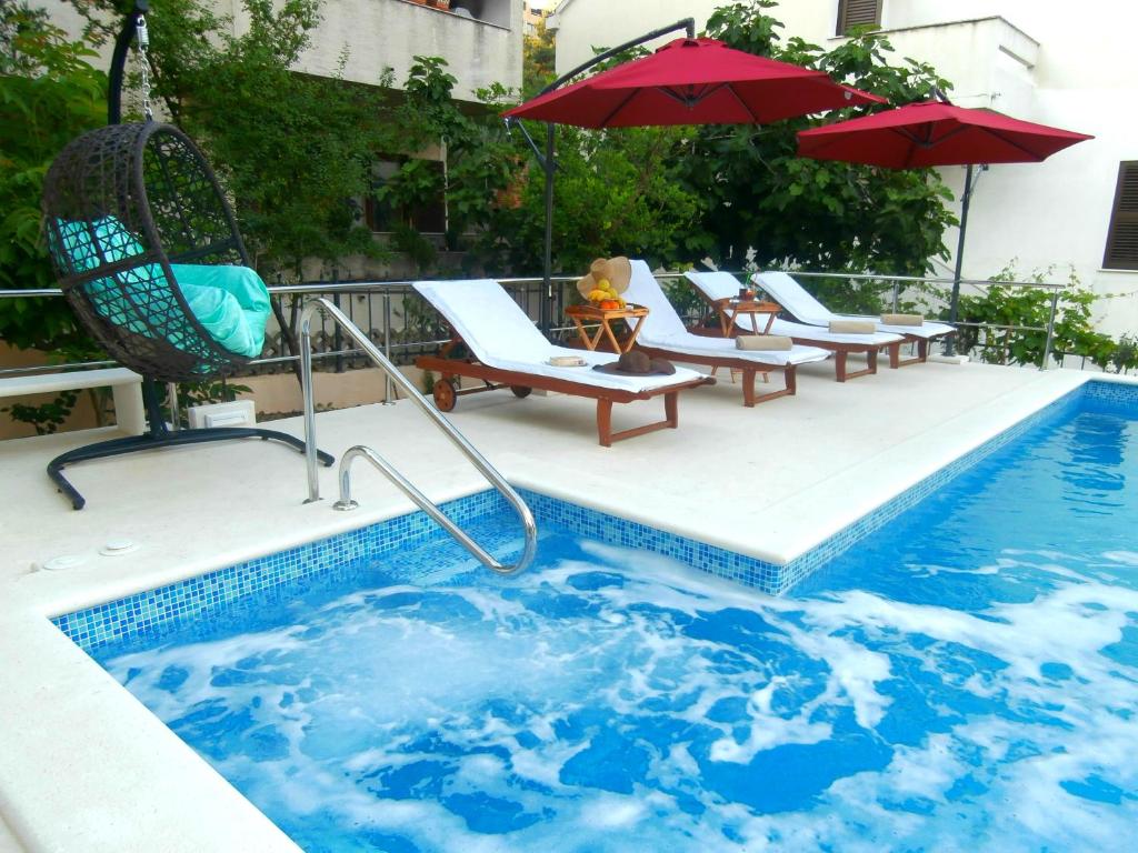 a swimming pool with chairs and umbrellas on a building at Apartments Cordis in Split