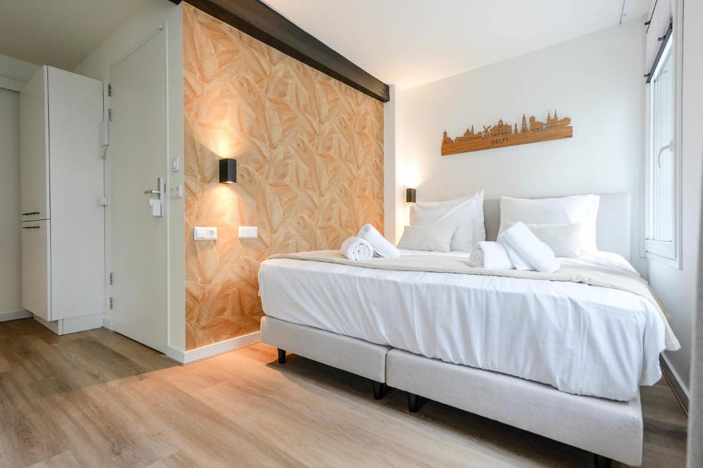 een slaapkamer met een groot wit bed en een muur bij Deluxe 20m2 Canal View in Delft
