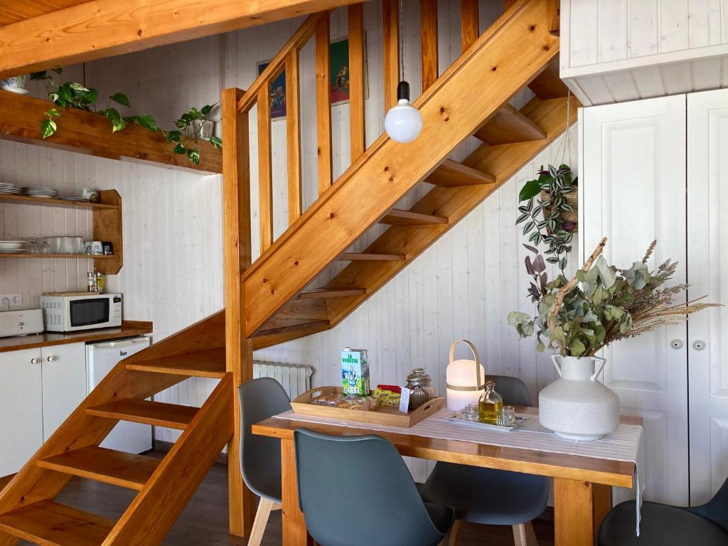 une cuisine avec une table en bois, des chaises et un escalier dans l'établissement Acogedora casa en Rinlo, en la villa de Ribadeo, à Ribadeo