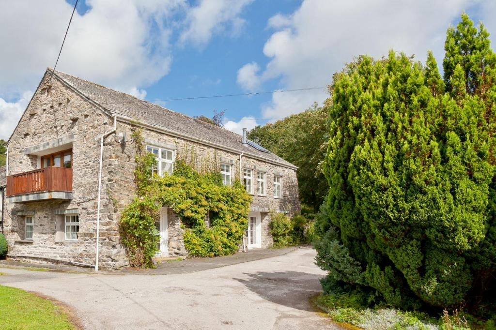 an old stone house with a tree in front of it at Charcoal House in Coniston