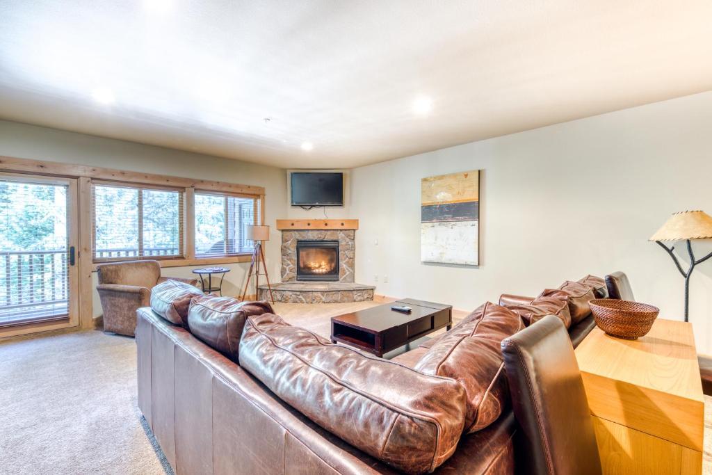 a living room with a leather couch and a fireplace at #101 Grand Lodge South Master Suite in Government Camp
