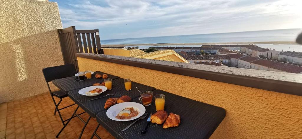 una mesa con platos de comida en el balcón en T2 avec une vue panoramique sur la mer, en Saint Pierre La Mer