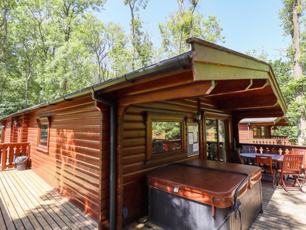 a log cabin with a deck and a table at 64 Acorn Lodge Kenwick Park in Louth