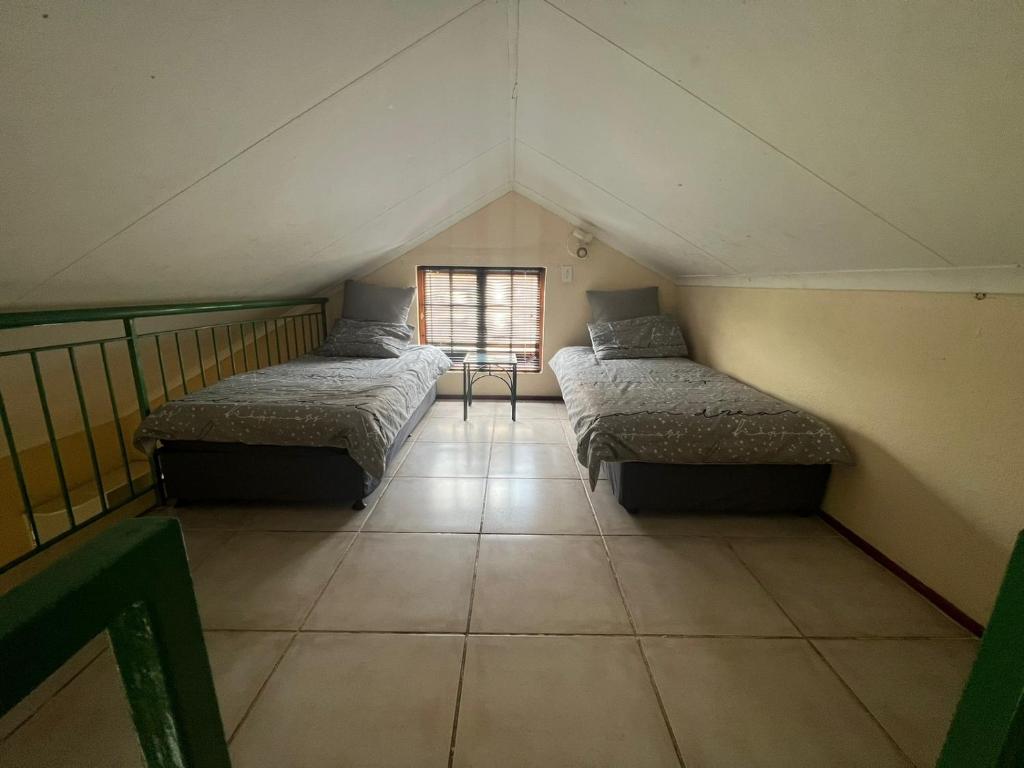 a attic room with three beds and a window at Pendleberry Holiday Resort - Unit 41 in Bela-Bela