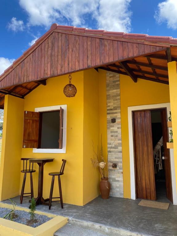 una casa amarilla con techo rojo en Chalé Entre as Pedras en Serra de São Bento