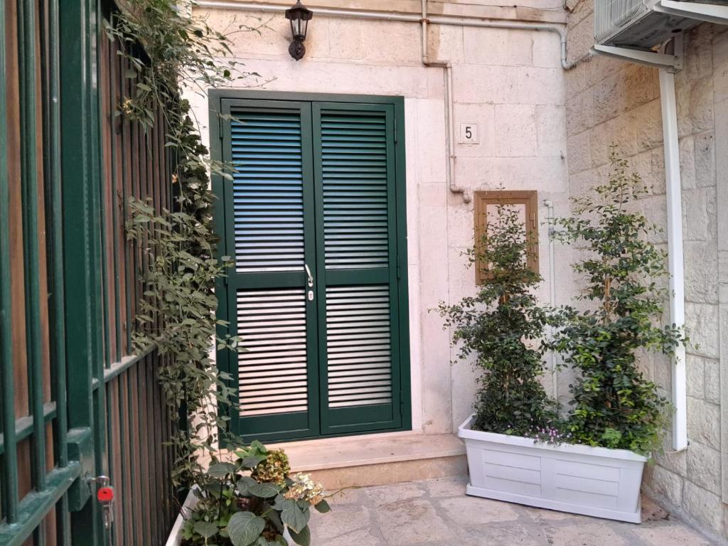 une porte verte et deux plantes en pot à côté d'un bâtiment dans l'établissement Arco Felice, à Giovinazzo