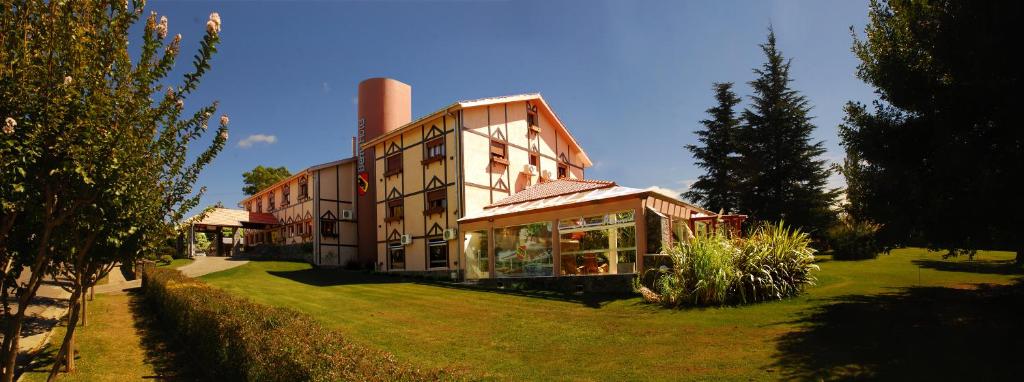 ein großes Gebäude auf einem Grasfeld vor der Unterkunft in der Unterkunft Berna Hotel & Spa in Villa General Belgrano