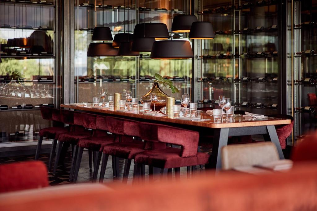 a long table in a restaurant with red chairs at Van der Valk hotel Veenendaal in Veenendaal