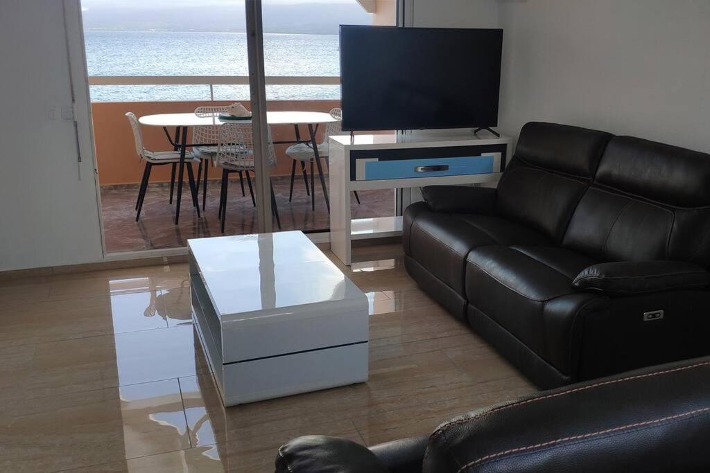- un salon avec un canapé, une télévision et une table dans l'établissement Appart. T2 de luxe +jacuzzi, vue mer et côté plage, au Gosier