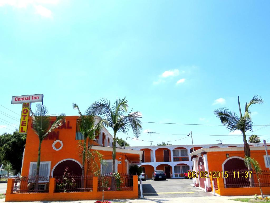 ein orangefarbenes Gebäude mit Palmen auf einem Parkplatz in der Unterkunft Central Inn Motel in Los Angeles