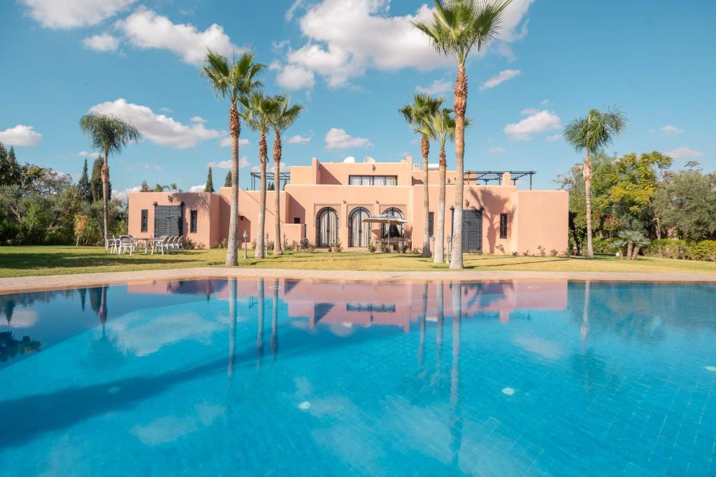 a house with palm trees in front of a swimming pool at Janat Al Atlas Resort & Spa in Marrakech