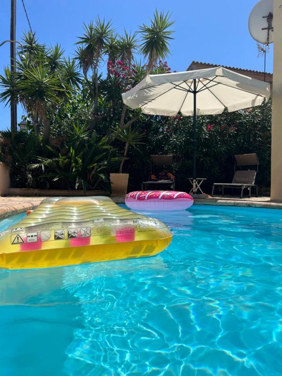 una piscina con una balsa inflable y una sombrilla en Casa Heidi, en Cala Santanyi