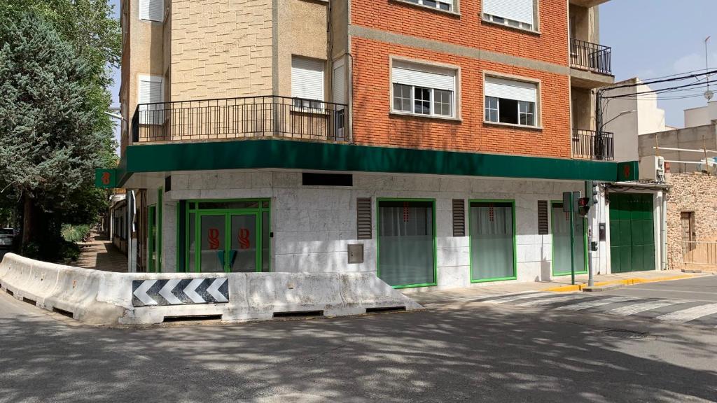 a building with green doors on the side of a street at Apto. Singular en la Mancha Banco de Inversiones in Argamasilla de Alba