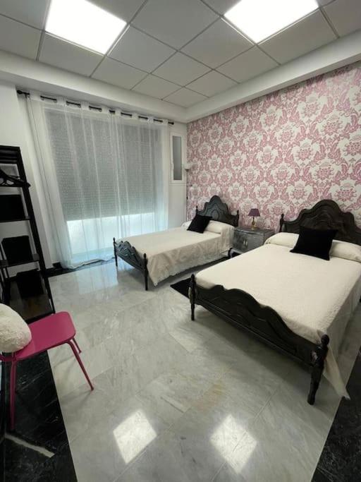 a room with two beds and a chair in it at Apto. Singular en la Mancha Banco de Inversiones in Argamasilla de Alba