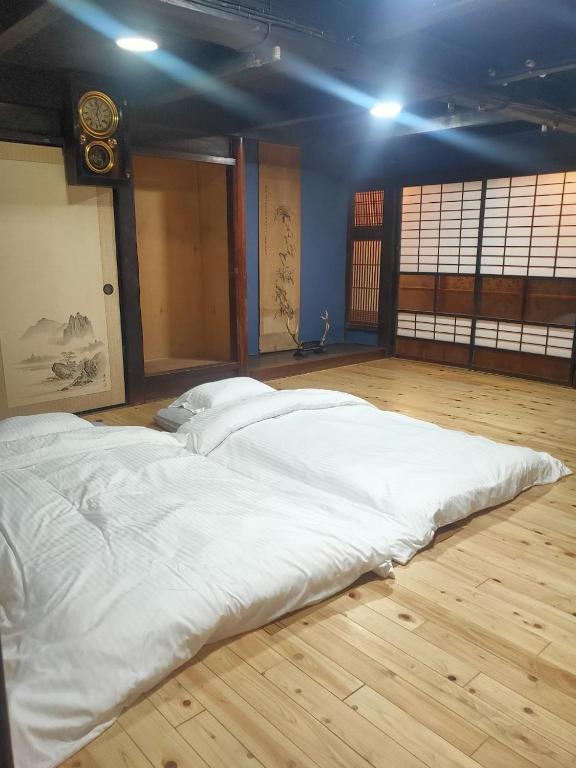 a large white bed in a room with a wooden floor at Momiji hostel in Minami Aso
